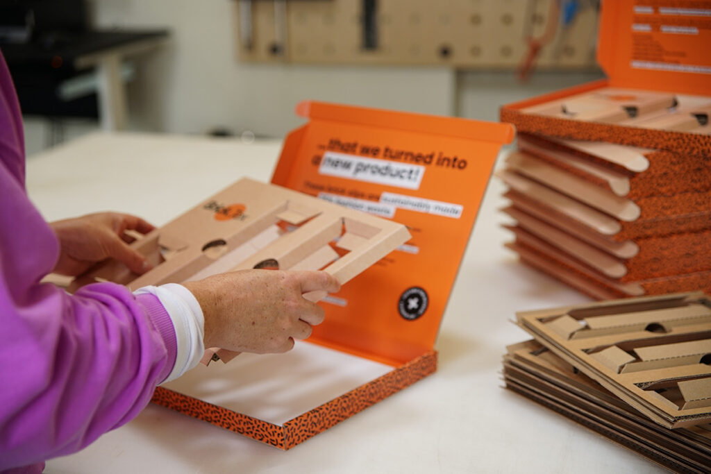 Lady folding a corrugate card fitment to adrop into a packaging prototype