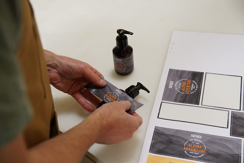 Man applying a label to a amber plastic bottle