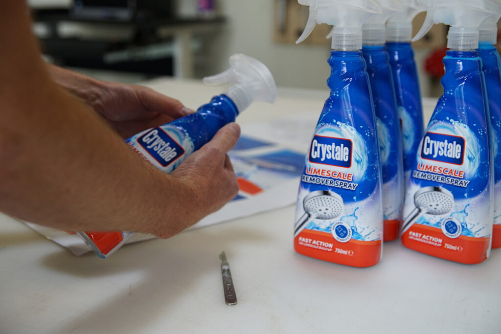 Man applying shrink sleeve prototypes to a trigger spray bottle